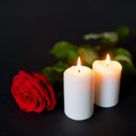 red rose and burning candles over black background