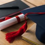 Selective focus of notebooks with pen, diploma and graduation cap on wooden background