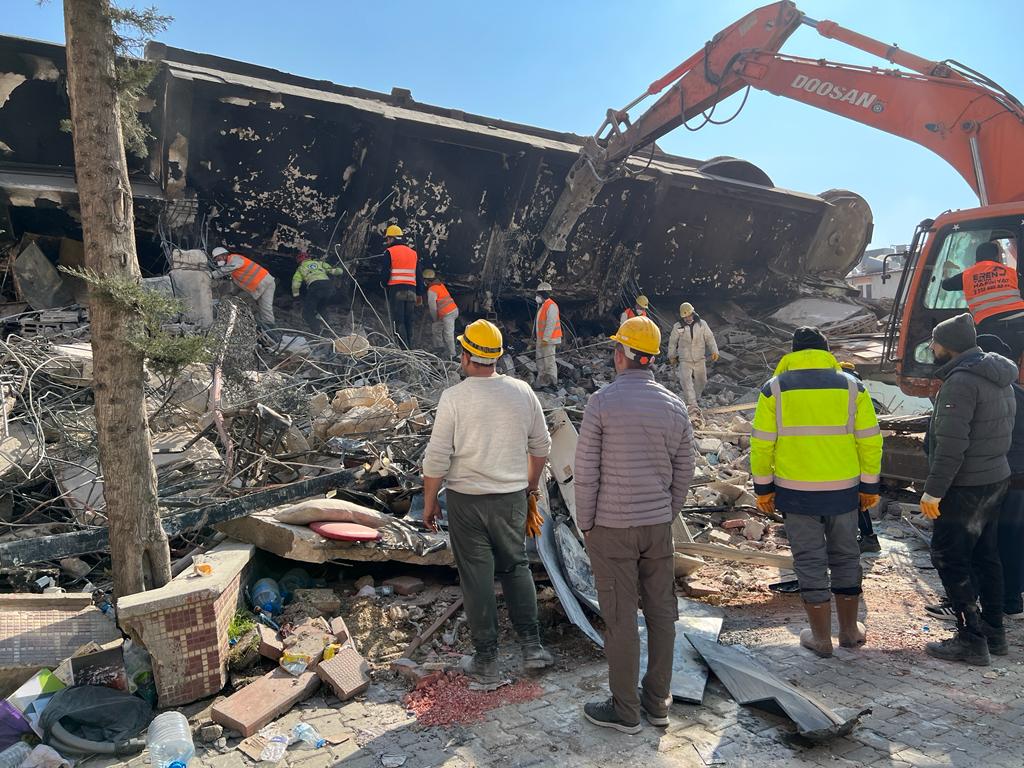 Rescue and search teams gather around the building where a family is trapped underneath in Antakya 