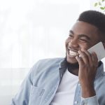 Cheerful african american employee having pleasant phone call at work