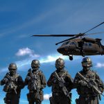 four soldiers carrying rifles near helicopter under blue sky