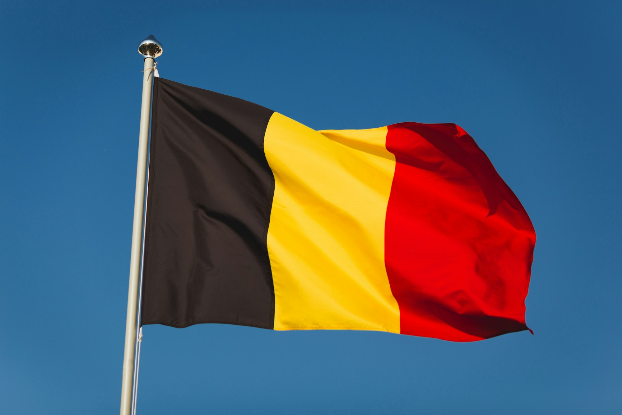 Flag of Belgium on mast. National flag against wind blue sky