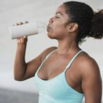 Fit african girl drinking water after sport workout outdoor