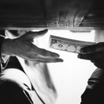 Hands passing money under table corruption bribery