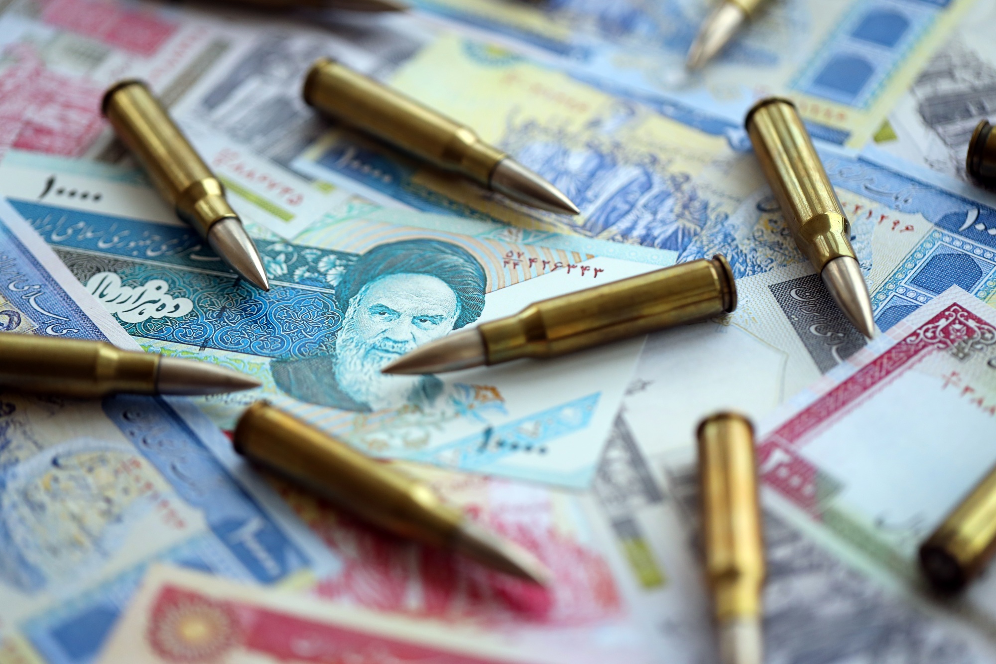 Many bullets and iranian rials money bills close up