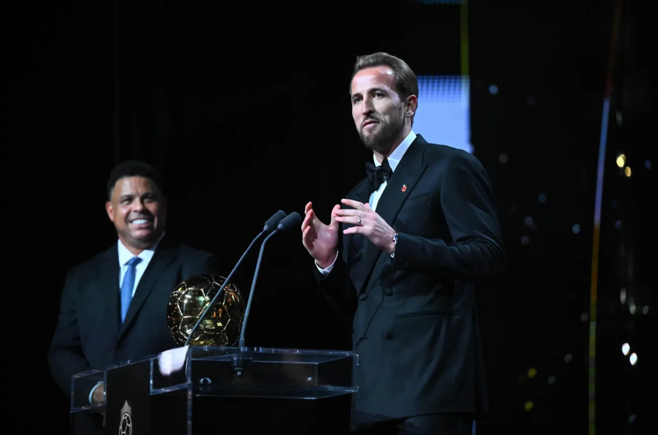 Harry Kane en costume au micro, à côté du trophée du Ballon d’Or.
