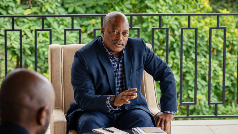 Joseph Kabila assis dans un fauteuil. Photographie d’illustration retouchée avec l’aide de l’IA.