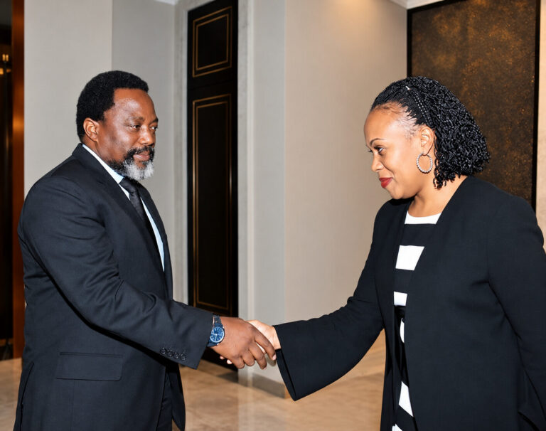 Marie-Ange Mushobekwa et Joseph Kabila se serrant la main sur une photographie fournie à la rédaction, retouchée par IA.